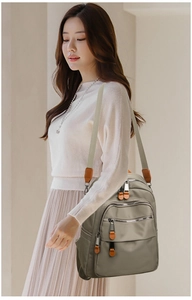 Detailed shot of grey-brown nylon backpack with multi-zipper compartments and shoulder strap