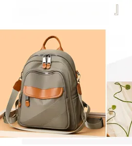 Detail of gray-green nylon backpack with brown leather accents and side pockets