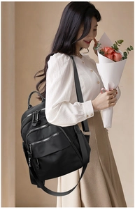 Side view of black nylon backpack on a model showing large capacity and multi-pocket layout