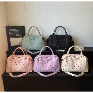 Five colors of strawberry print corduroy travel bags displayed on a modern step stand