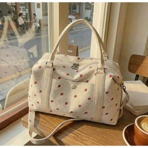 Detail of strawberry embroidery on corduroy travel bag with metal buckle pocket