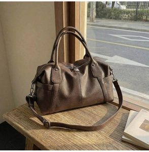 Close-up of retro brown tote bag with leather texture and metal zipper on wooden bench