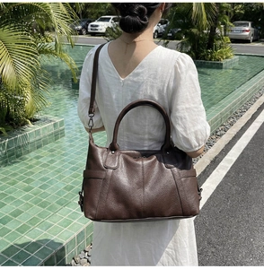 Outdoor shot of a vintage brown leather tote bag with grainy texture and shoulder strap