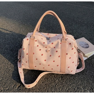 Detailed texture of pink corduroy travel bag with sweet red strawberry prints