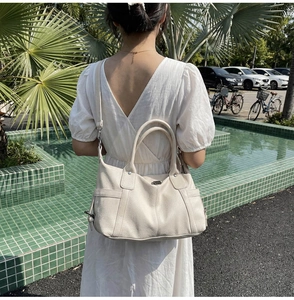 Off-white lychee grain leather tote bag shown on model with adjustable strap and side pocket