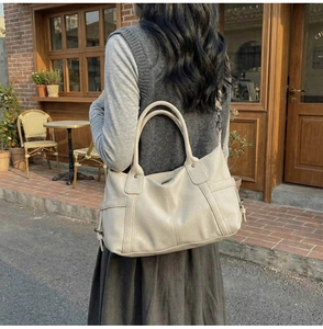 Detail of creamy tote bag with lychee leather texture and side buckle design