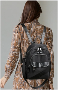 Detail of multi-layer zipper pockets and flap pouch on black water-resistant nylon backpack