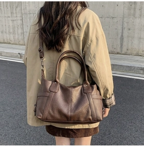 Detail of dark brown tote bag featuring pebbled leather texture and adjustable shoulder strap