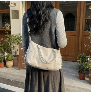 Outdoor lifestyle shot of cream leather tote bag with long strap for daily commute