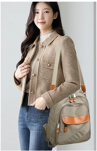 Detail of multi-compartment nylon backpack featuring contrast leather pullers and front zip pocket