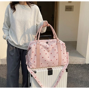 Detail of pink corduroy travel bag with strawberry print on a white suitcase