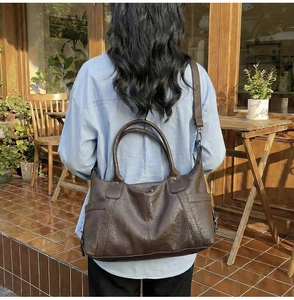 Close-up of vintage brown tote bag featuring premium lychee texture and side pocket detail