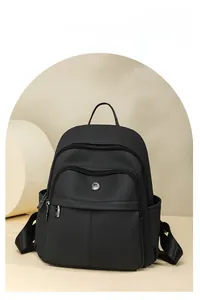 Detail of black PU leather backpack showing fine texture and multiple zipper compartments