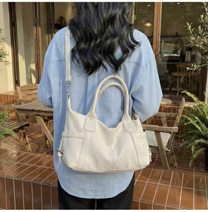 Close-up of a beige leather tote bag with lychee texture and detachable shoulder strap