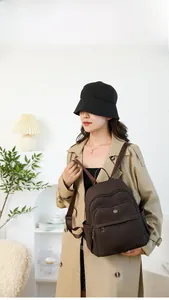 Detail view of coffee-colored nylon backpack with multi-layer zippers and side pockets
