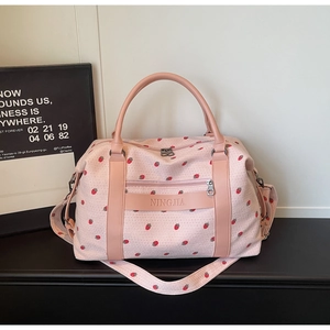 Detail of pink strawberry print travel bag showing leather handles and zipper pocket