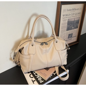 Detail of off-white lychee texture leather boston bag with side pockets and dual handles