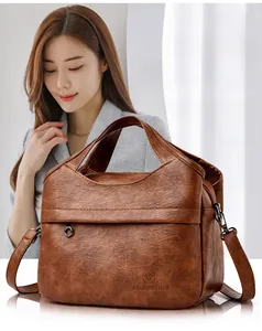 Close-up of a brown vintage leather handbag with adjustable strap on a fashion model