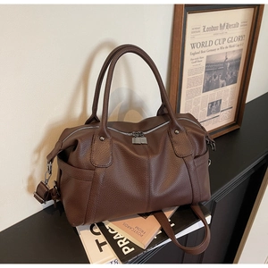 Detail of brown litchi pattern leather Boston bag with silver zipper and double handles