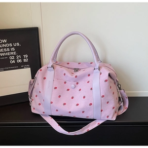 Detail of lavender corduroy travel bag featuring red strawberry prints and carry handles