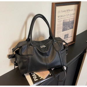 Close-up of black litchi pattern leather tote bag with dual handles and side pocket