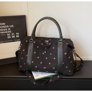 Detail of strawberry print travel bag with leather handles and detachable strap