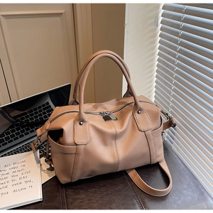 Close-up of pebble leather Boston bag featuring dual handles and adjustable shoulder strap