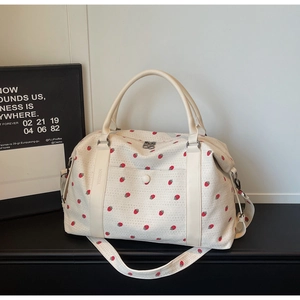 Macro detail of strawberry print canvas travel bag with premium cream leather handles