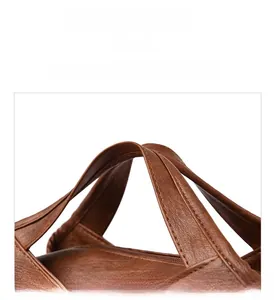 Detail of reinforced handles with stitching and lychee texture on brown handbag