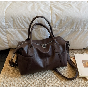 Close-up of deep brown litchi pattern leather texture and silver zipper of the tote bag