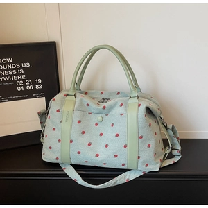 Detail view of mint green corduroy travel bag with red strawberry print and sturdy handles