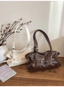 Détail de sacs à bandoulière en cuir avec ceintures à œillets en crème et marron