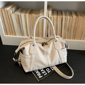 Detail of cream lychee leather texture and gunmetal hardware on a vintage tote bag
