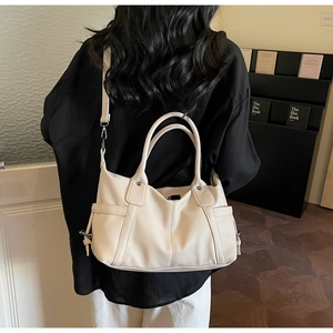 Cream tote bag with pebbled texture and side pocket shown worn by a model