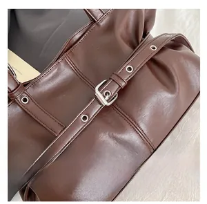 Détail du sac cabas en cuir PU marron foncé avec œillets argentés et texture plissée