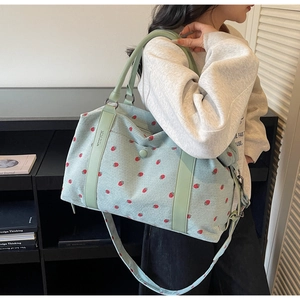 Detailed shoulder view of a mint green corduroy tote bag with strawberry print and leather straps