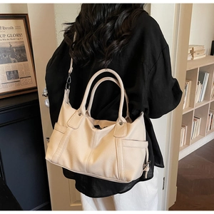 Detail of beige lychee textured tote bag featuring side pockets and adjustable strap