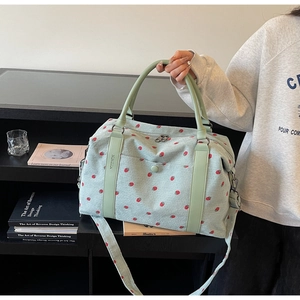 Detail of mint green corduroy travel bag with strawberry embroidery and dual handles