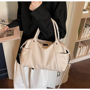 Close-up of beige lychee texture tote bag with dual handles and gunmetal hardware detail