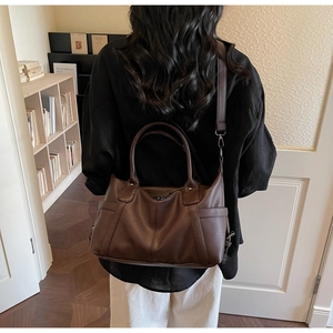 Detail of dark brown pebble leather tote bag with sturdy handles and adjustable strap