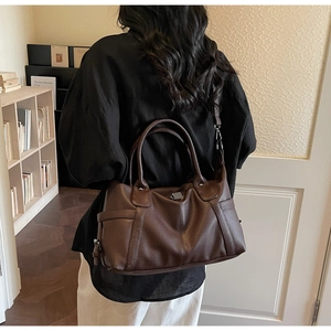 Detailed view of dark brown tote bag with pebble leather texture and reinforced handles