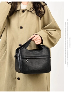 Detail of a vintage black leather tote bag with lychee texture and metal ring zipper