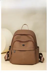 Detail view of brown twill fabric backpack showing zippers and side pockets on a stand