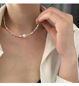 Gros plan d'un collier asymétrique en perles d'argent avec une perle blanche sur un mannequin