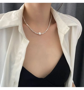 Gros plan d'un collier de perles asymétrique avec billes en argent porté au cou
