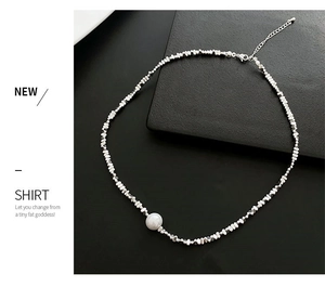 Détail macro du collier asymétrique en perles argentées avec pendentif perle blanche