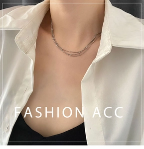 Détail d'un collier à plusieurs rangs argenté porté sur une chemise blanche
