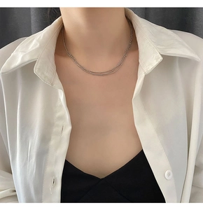 Gros plan d'un collier multicouche argenté perlé porté sur un chemisier blanc chic