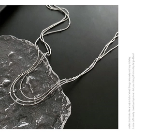 Détail du collier multi-rangs en chaîne serpent argentée avec des perles métalliques