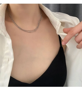 Détail d'un collier argenté à plusieurs rangs avec de fines perles porté sur un mannequin chic